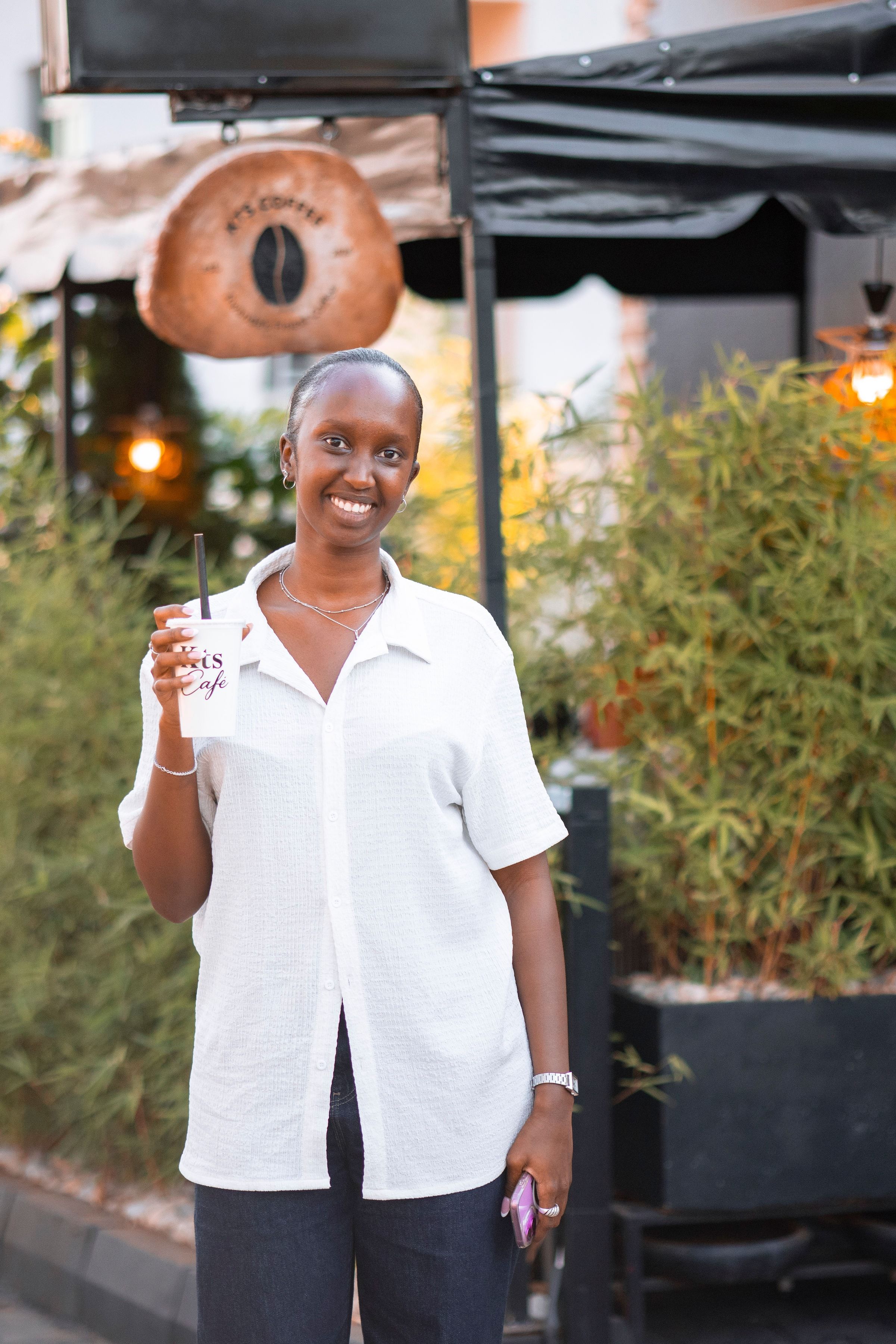 A smiling guest holding up a freshly served KTS Café cup by the entrance
