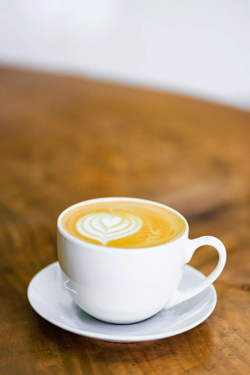 A hot cappuccino with heart latte art on a live-edge wooden table at KTS Café