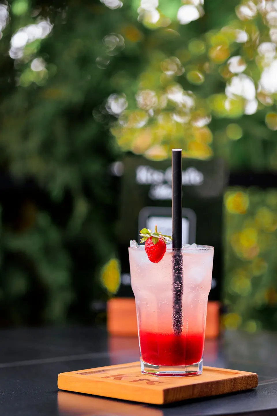 A strawberry fizz with a fresh strawberry on a KTS Café coaster on the garden terrace
