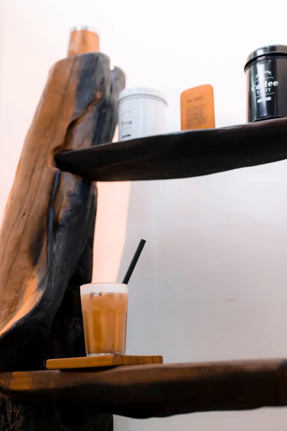 Coffee tins, the wooden menu card and an iced coffee on the rustic driftwood shelves inside KTS Café