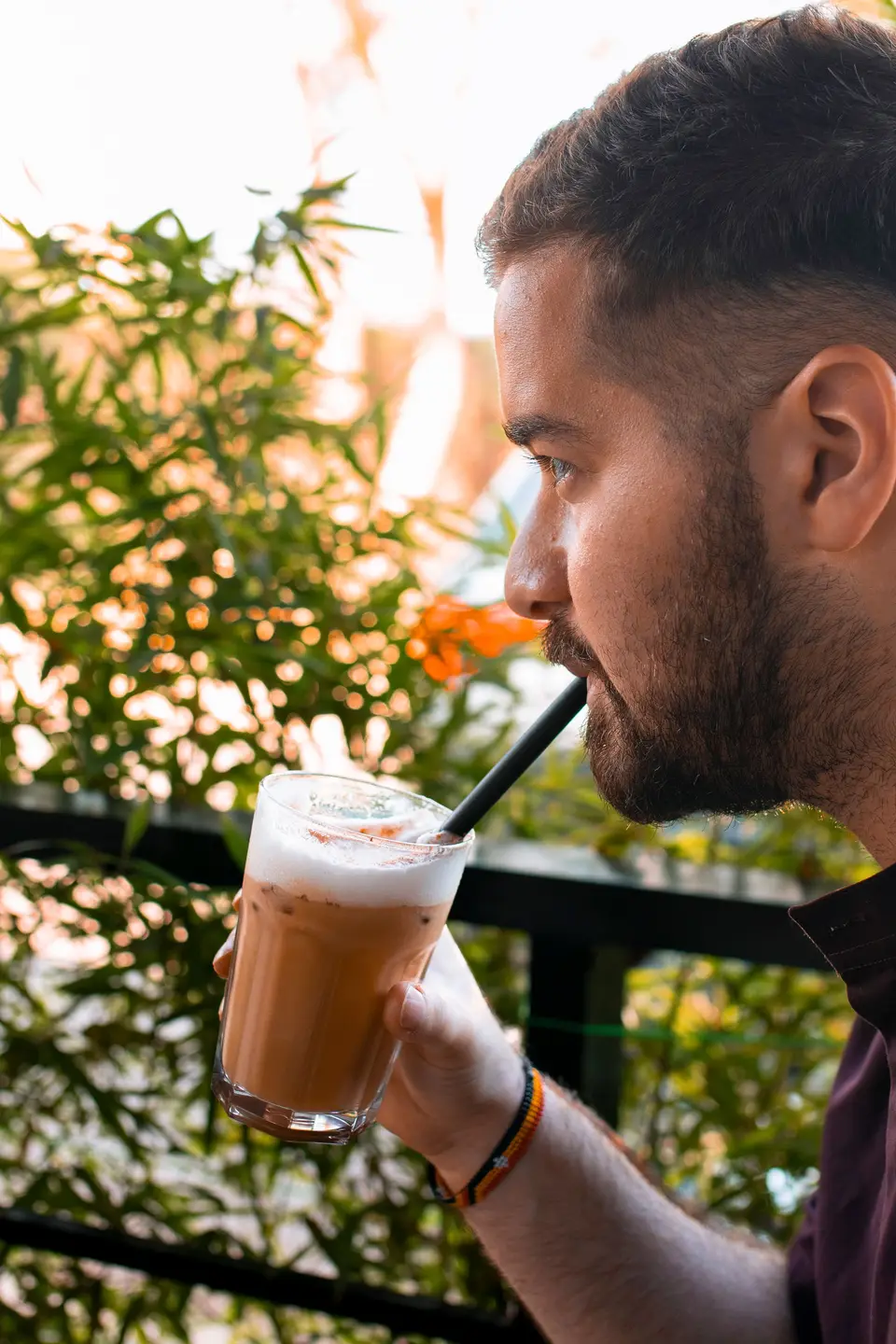 A guest savouring an iced latte through a straw on the KTS Café terrace